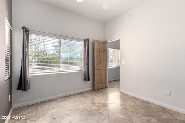 empty room with ceiling fan, baseboards, and a wealth of natural light