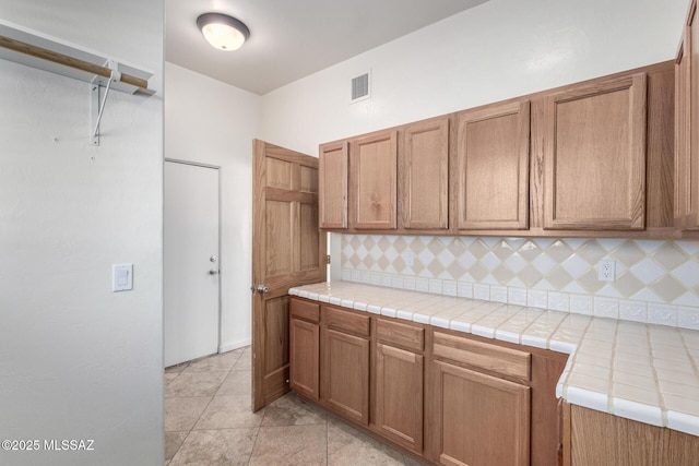 kitchen with tasteful backsplash, light tile patterned flooring, and visible vents