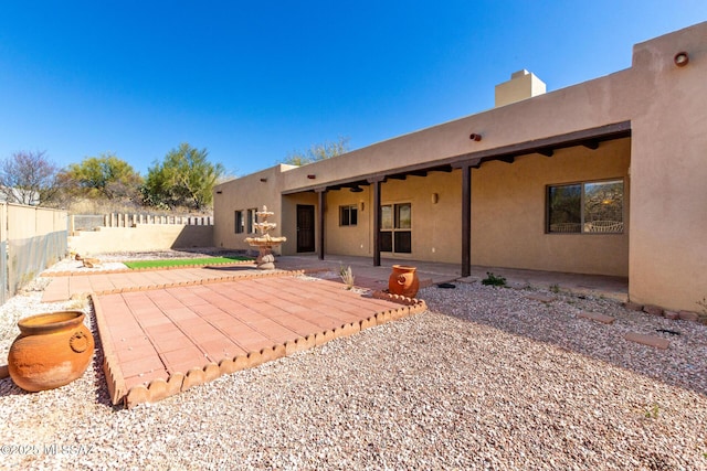 back of house with stucco siding, a fenced backyard, and a patio