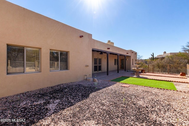 rear view of property featuring fence, a patio, and stucco siding