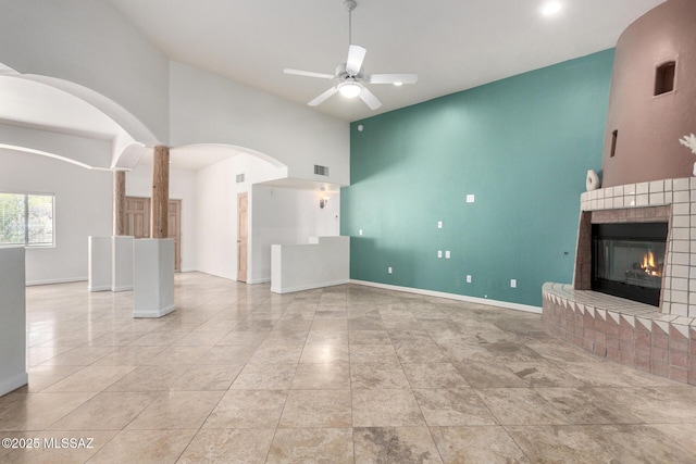 unfurnished living room with a fireplace, visible vents, ceiling fan, high vaulted ceiling, and baseboards