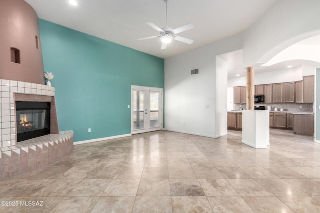 unfurnished living room with ceiling fan, a fireplace, visible vents, and baseboards