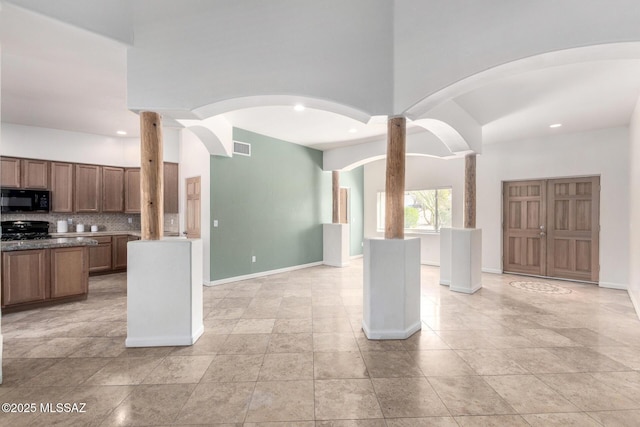 kitchen featuring black microwave, visible vents, open floor plan, backsplash, and range with gas cooktop