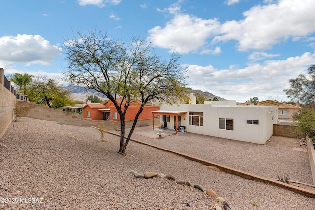 rear view of house with stucco siding, a patio, and a fenced backyard