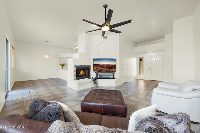 living area featuring visible vents, a lit fireplace, and ceiling fan