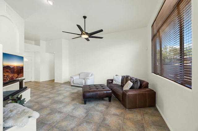 living area with baseboards and ceiling fan