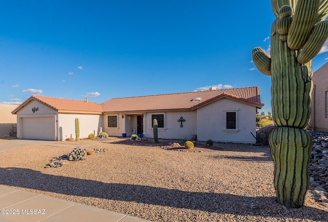 view of front facade featuring driveway, an attached garage, a tile roof, and stucco siding