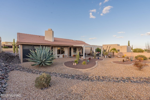 rear view of property with a patio, a chimney, stucco siding, a pergola, and a tiled roof