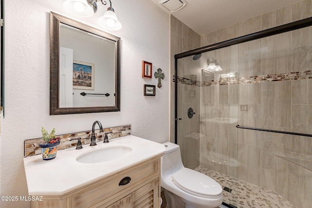 full bath with toilet, a textured wall, a shower stall, and vanity