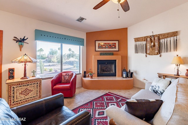 tiled living room with ceiling fan, a fireplace, visible vents, and baseboards