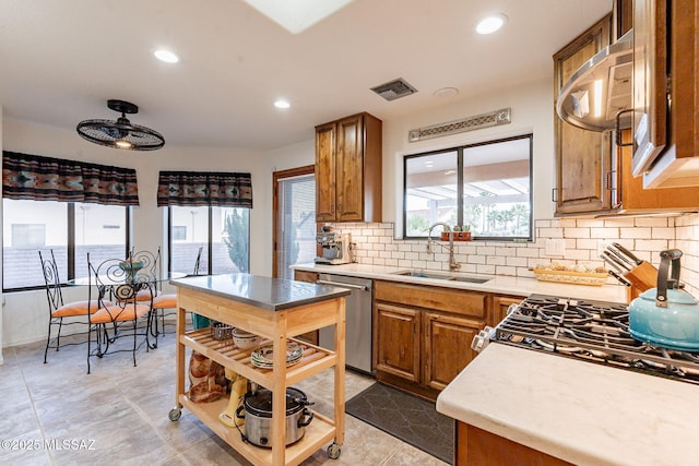 kitchen featuring a sink, visible vents, light countertops, stainless steel dishwasher, and brown cabinets