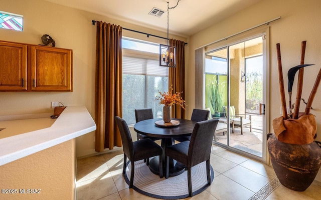 dining area with light tile patterned floors, visible vents, and an inviting chandelier