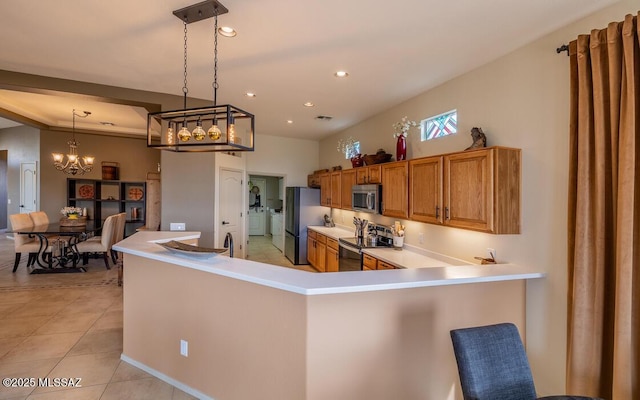 kitchen with light tile patterned floors, stainless steel appliances, light countertops, hanging light fixtures, and brown cabinetry