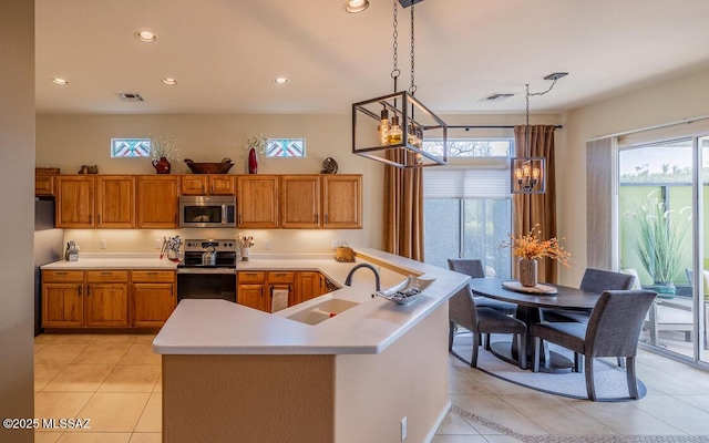 kitchen with visible vents, brown cabinetry, appliances with stainless steel finishes, light countertops, and a sink