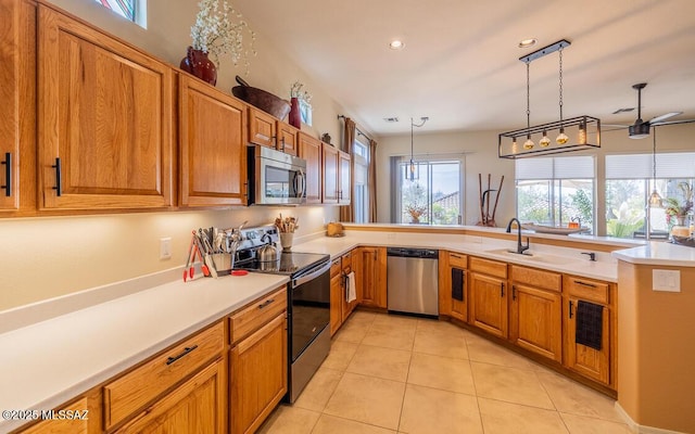 kitchen featuring light tile patterned floors, stainless steel appliances, a sink, and brown cabinets