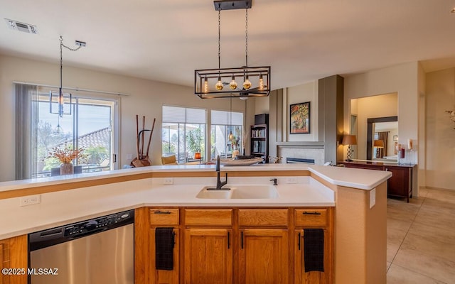 kitchen featuring brown cabinetry, visible vents, a sink, and stainless steel dishwasher