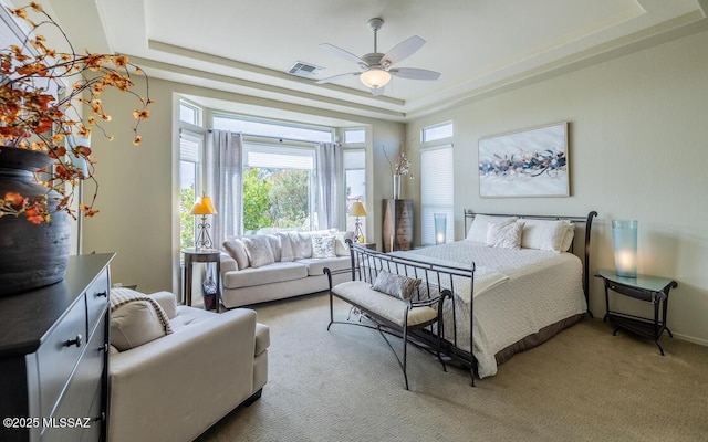 bedroom featuring a ceiling fan, a tray ceiling, light carpet, and visible vents