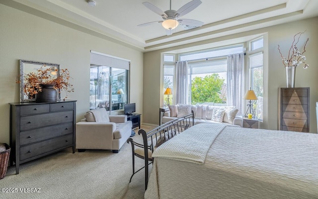 bedroom featuring light carpet, multiple windows, a tray ceiling, and a ceiling fan