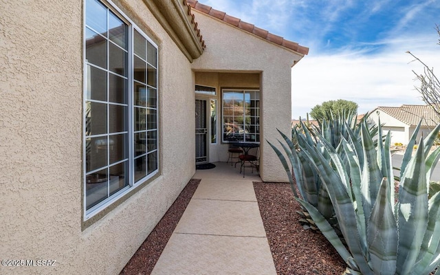 exterior space with a patio, a tiled roof, and stucco siding