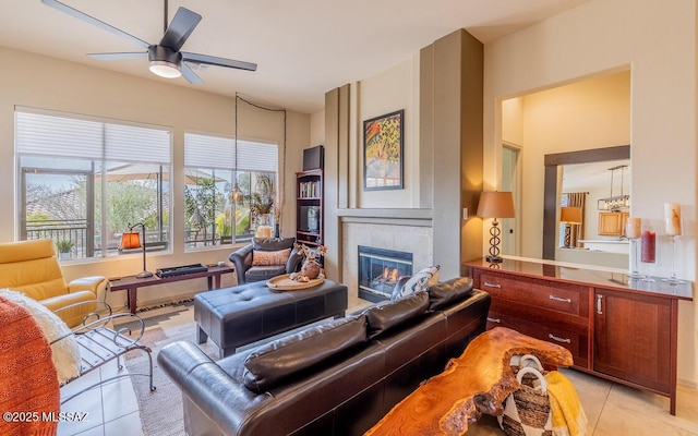 living room featuring light tile patterned floors, ceiling fan, and a tiled fireplace