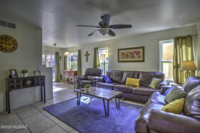 living area with a ceiling fan, visible vents, a textured ceiling, and light tile patterned flooring