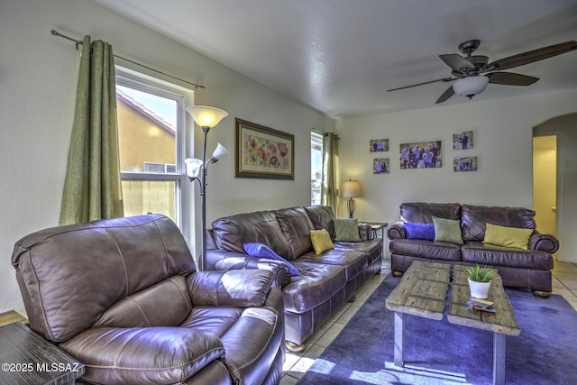 tiled living area with arched walkways, visible vents, and ceiling fan