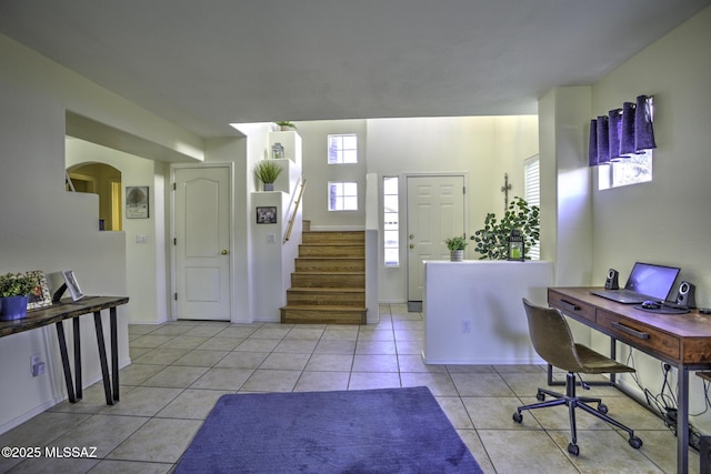 entryway with stairway, arched walkways, and light tile patterned floors