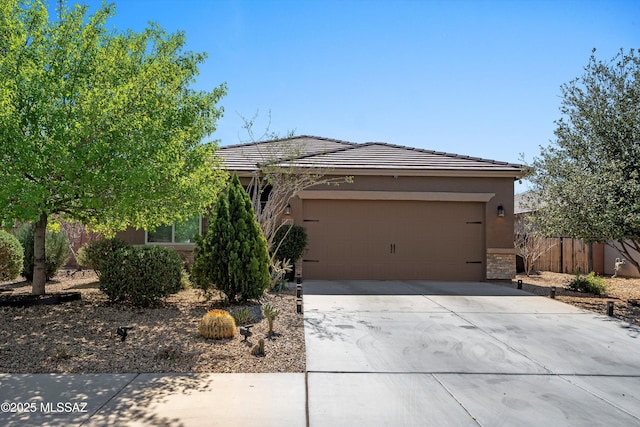 view of front facade with a garage, stucco siding, driveway, and a tiled roof