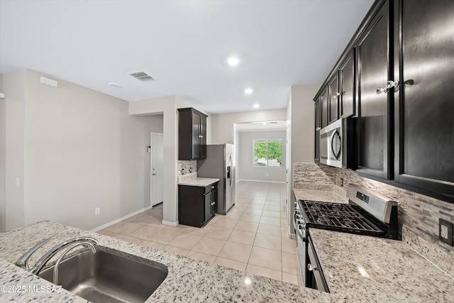 kitchen featuring visible vents, light stone counters, appliances with stainless steel finishes, light tile patterned flooring, and a sink