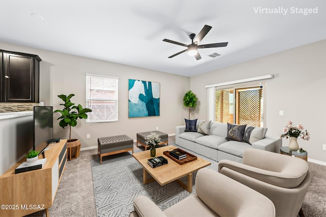 living room with visible vents, baseboards, a ceiling fan, and carpet flooring