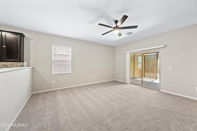 empty room featuring baseboards, plenty of natural light, light carpet, and ceiling fan