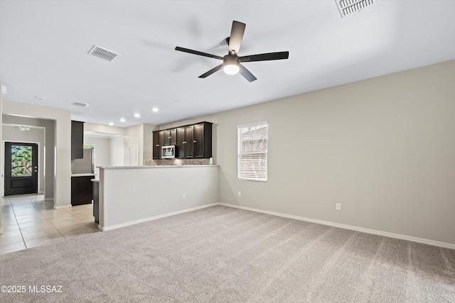 unfurnished living room with light tile patterned floors, visible vents, light carpet, and baseboards