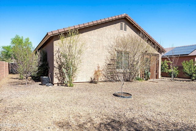 exterior space featuring stucco siding, a tiled roof, and a fenced backyard