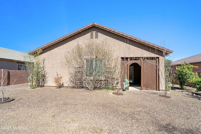 rear view of property with stucco siding and fence