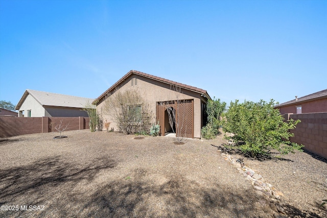 view of front of property with stucco siding, a tile roof, and a fenced backyard