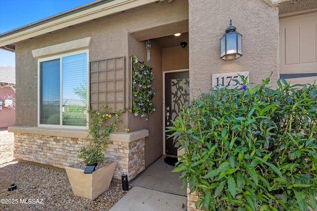 doorway to property featuring brick siding and stucco siding