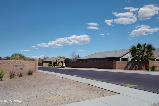 view of street featuring traffic signs, a residential view, sidewalks, and a gate