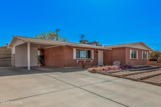 ranch-style home with a carport, concrete driveway, and brick siding