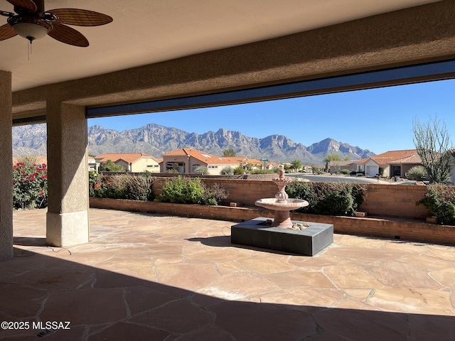 view of patio featuring fence, a mountain view, and a ceiling fan