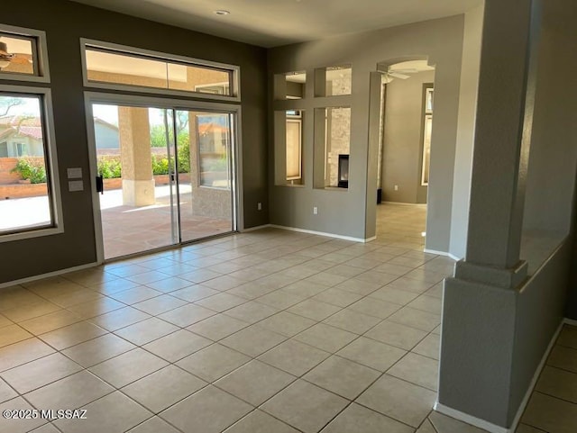 spare room with baseboards, arched walkways, and light tile patterned flooring