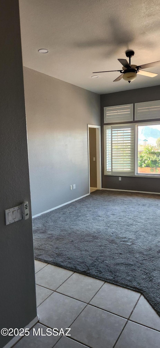 unfurnished room featuring a textured ceiling, carpet, tile patterned flooring, and a ceiling fan