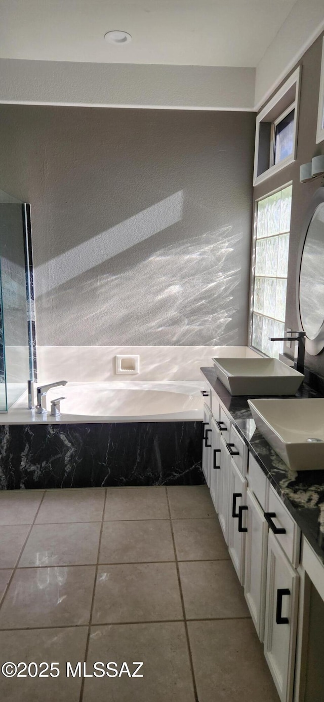 bathroom with a garden tub, double vanity, tile patterned flooring, and a sink