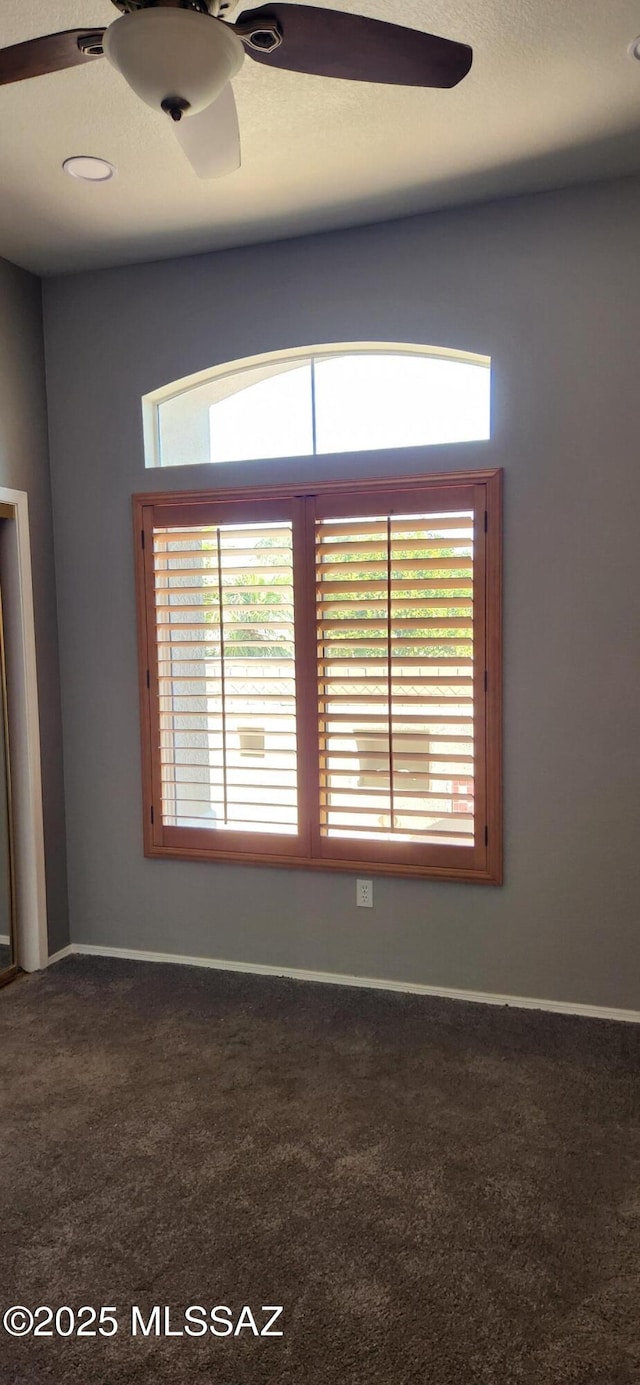 unfurnished room with carpet floors, baseboards, and a ceiling fan