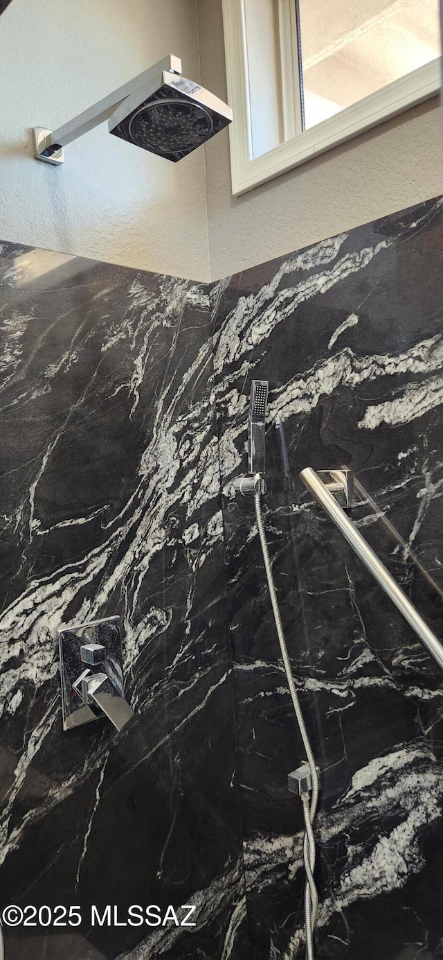 interior details with a marble finish shower and a textured wall