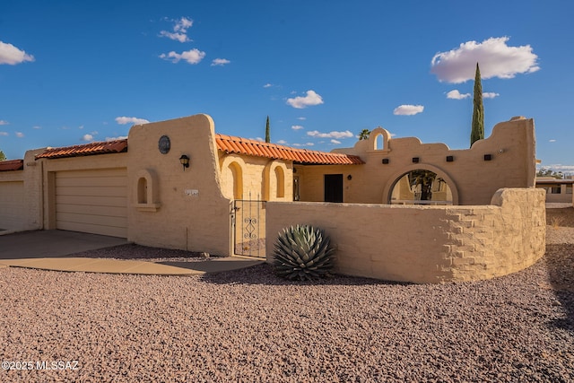 view of front of home with a garage, a fenced front yard, a gate, and stucco siding