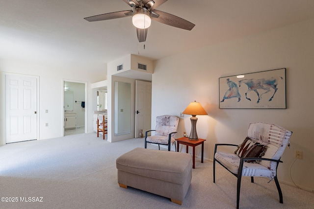 living area with carpet floors, visible vents, baseboards, and a ceiling fan