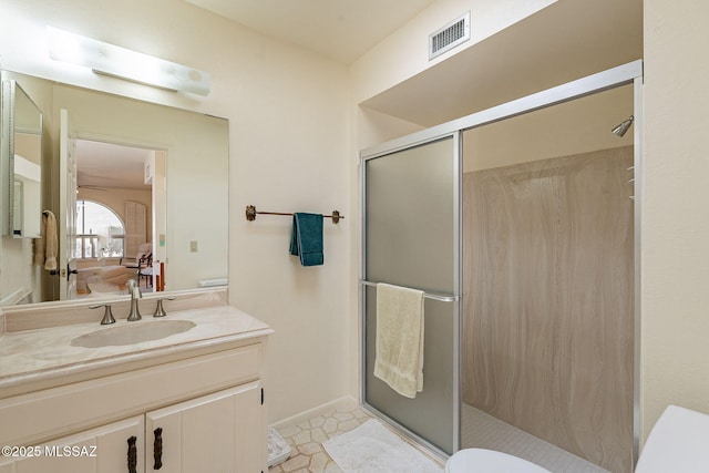 ensuite bathroom featuring vanity, a shower stall, visible vents, and connected bathroom