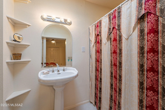 bathroom featuring ceiling fan and baseboards