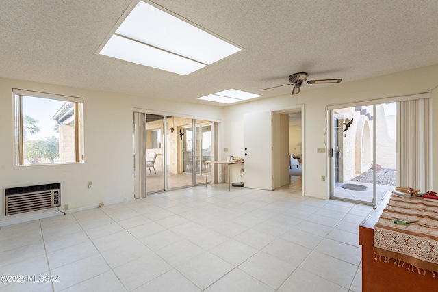 living room featuring a skylight, a ceiling fan, heating unit, a textured ceiling, and light tile patterned flooring