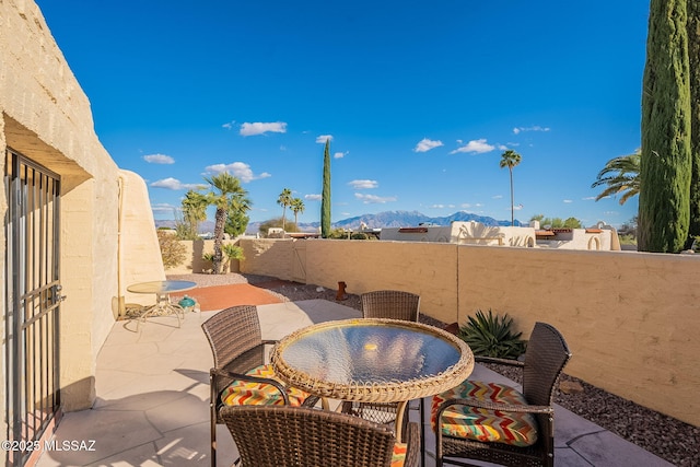 view of patio featuring outdoor dining space, a fenced backyard, and a mountain view